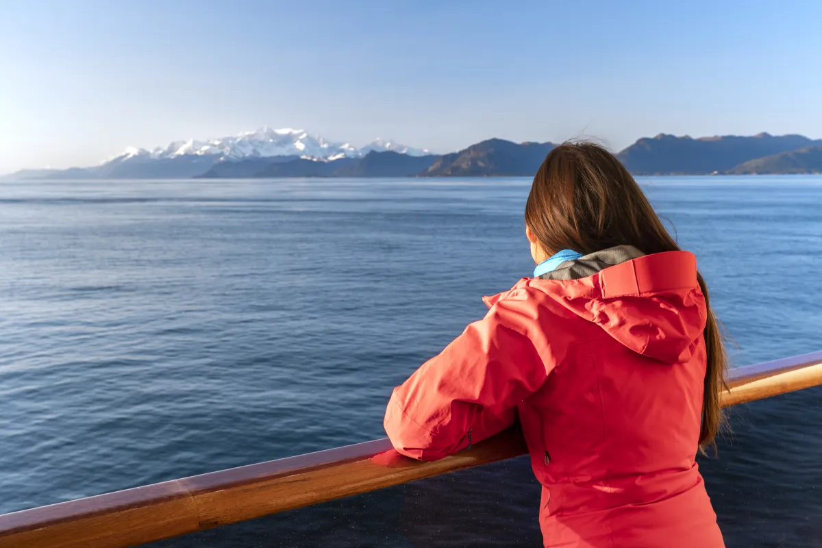  tourist looking at mountains landscape from balcony deck of ship